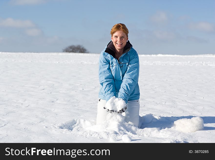 Nice woman kneeing in snow wanting to throw up a handful of snow. Nice woman kneeing in snow wanting to throw up a handful of snow