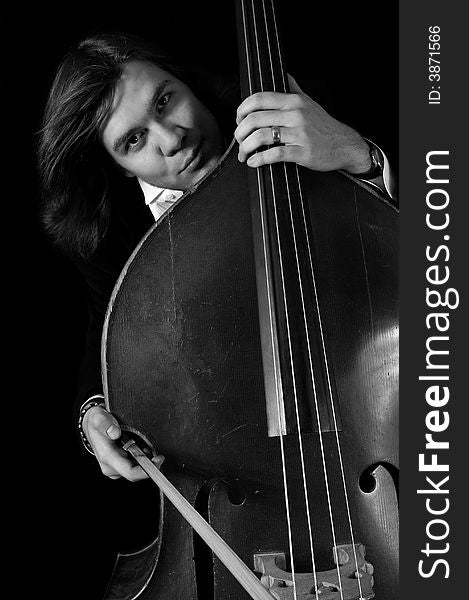 Melancholy musician with a contrabass over black background. bnw