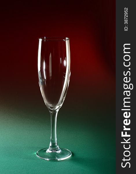 Single champagne glass on red and green background