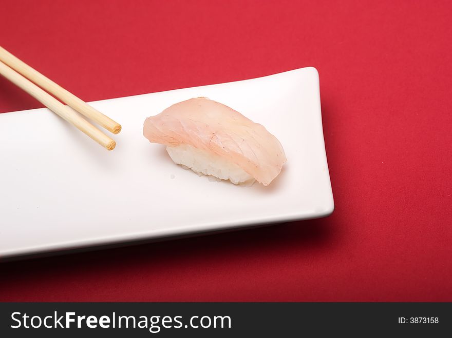 Sushi crude fish on a white plate over a reddish background