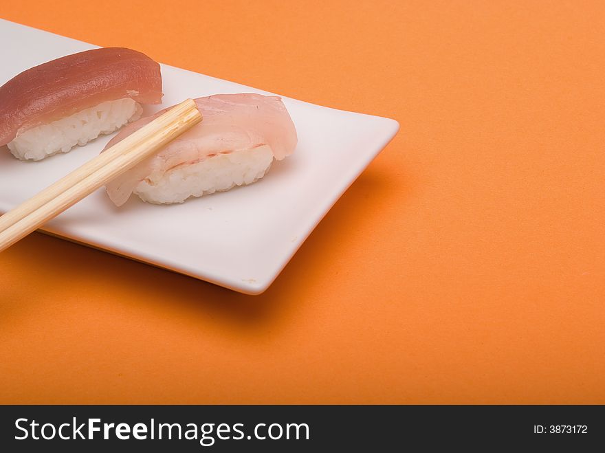 Sushi crude fish on a white  plate over an orange background