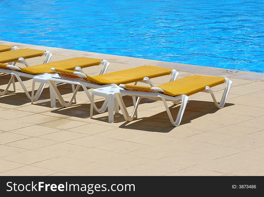 Pool restbeds around a pool with blue water background