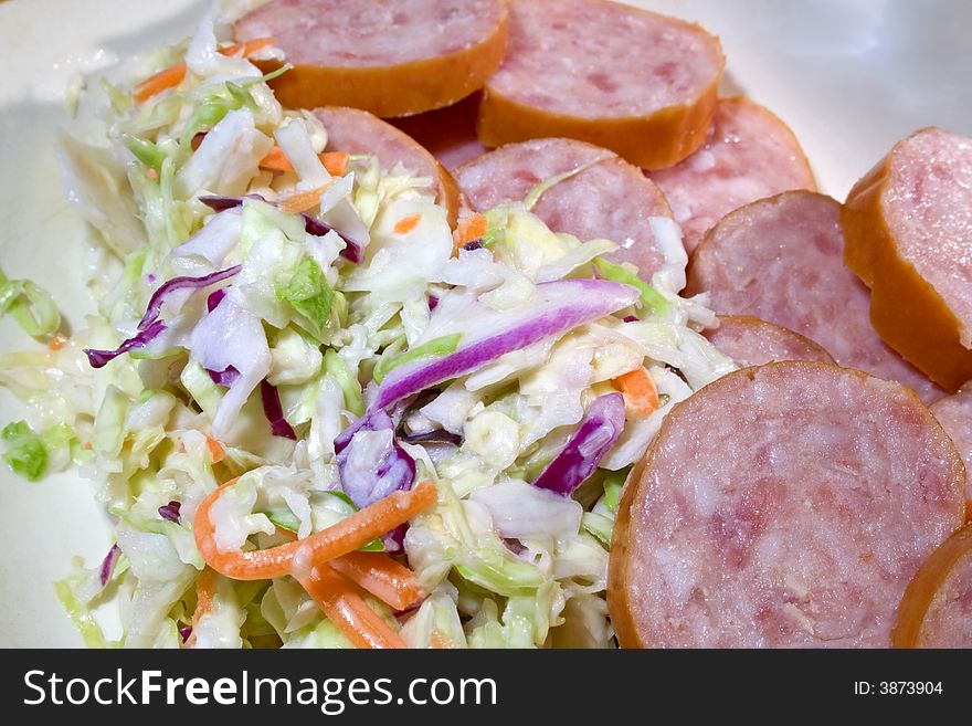 Sausage sliced with coleslaw for meal. Sausage sliced with coleslaw for meal