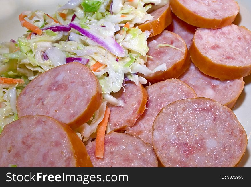 Sausage sliced with coleslaw in dish. Sausage sliced with coleslaw in dish