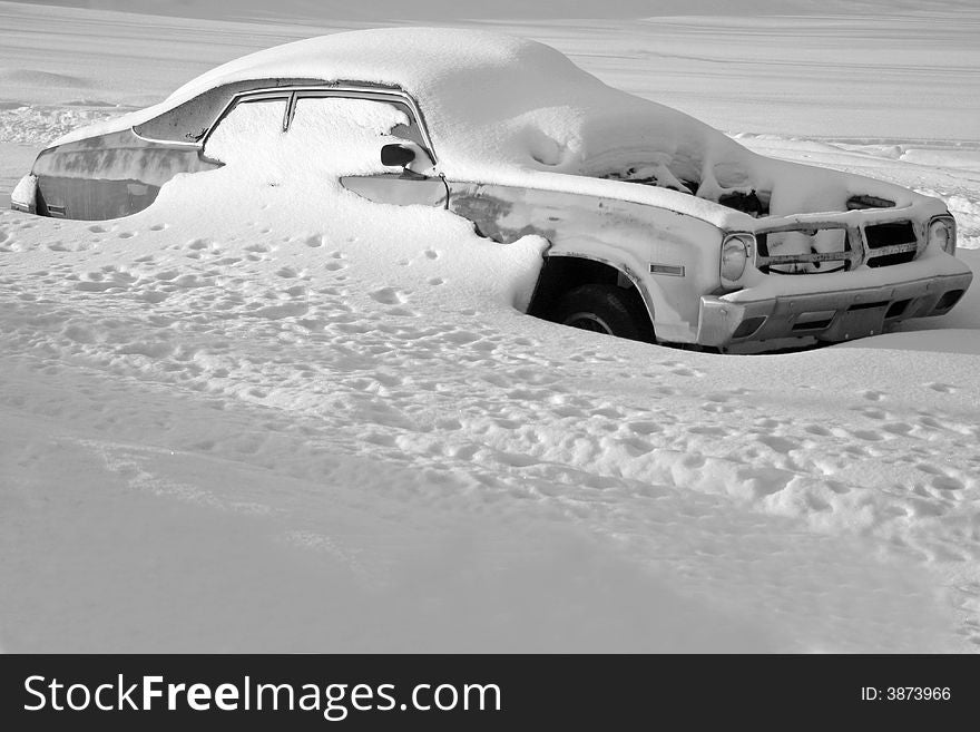 An abandoned old car buried under snow in a winter field. An abandoned old car buried under snow in a winter field