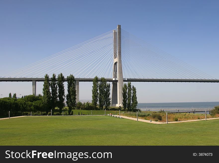 View of one of Lisbon's bridges with a grass lawn in foreground. View of one of Lisbon's bridges with a grass lawn in foreground