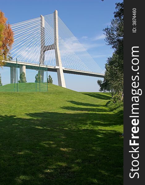 View of one of Lisbon's bridges with a grass lawn and trees in foreground. View of one of Lisbon's bridges with a grass lawn and trees in foreground