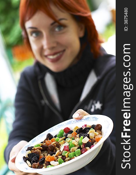 Young laughing red-haired woman offering candied fruits