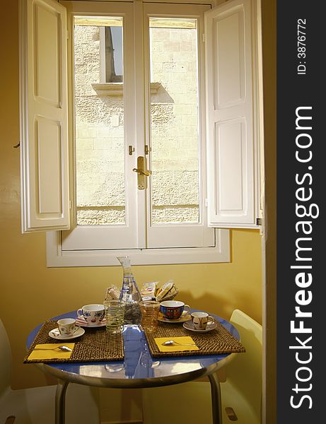 A table prepared for two breakfast near a window. A table prepared for two breakfast near a window