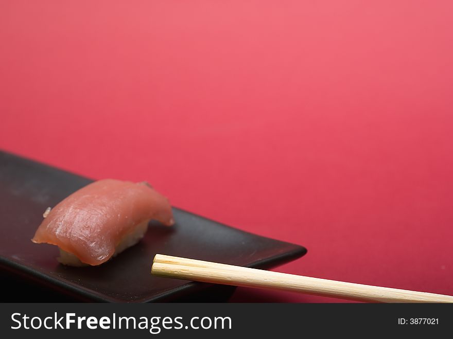 Sushi crude fish on a black plate over a reddish background
