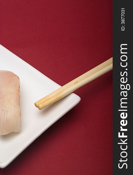 Sushi crude fish on a white plate over a reddish background