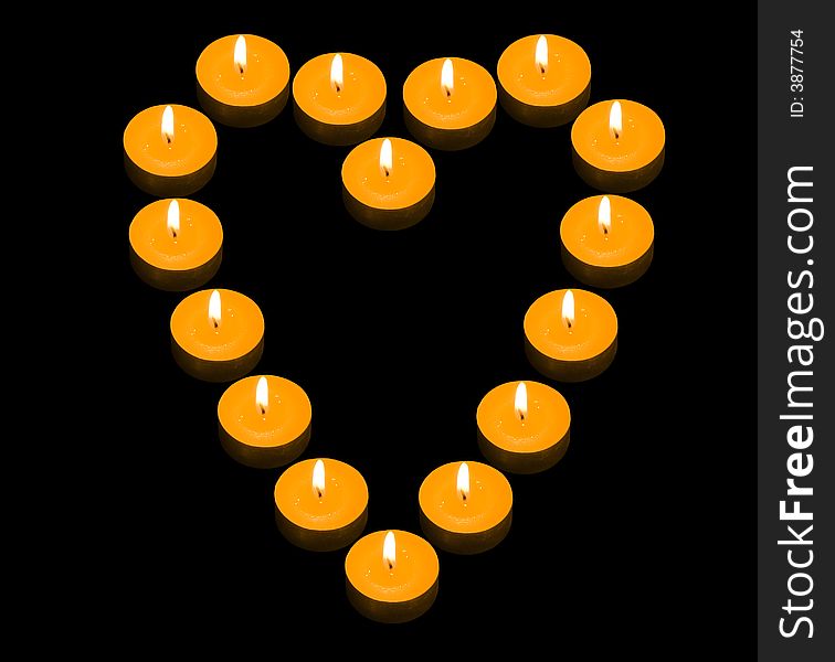 A group of burning candles forming a fiery heart on the black background. A group of burning candles forming a fiery heart on the black background
