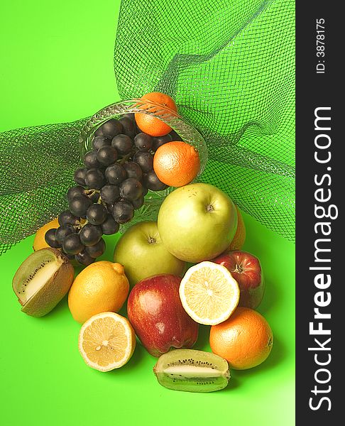 Rich assortment of fruit consisting of apples, citron, grapes, kiwi on a green background