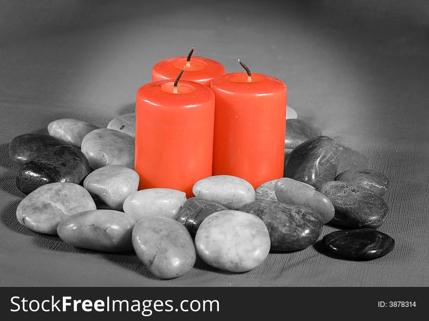 Three unlit red candles siitting in a pile of river rocks with only the candles in color. Three unlit red candles siitting in a pile of river rocks with only the candles in color