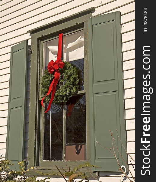 A window on an old house decorated with a wreath for Christmas. A window on an old house decorated with a wreath for Christmas