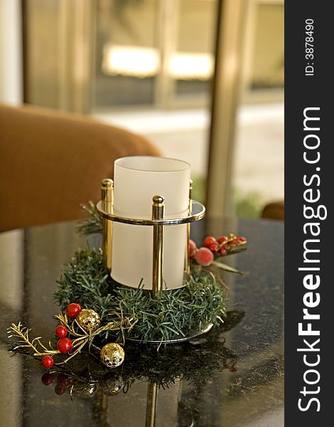 A white christmas candle in a holder decorated with holly and berries. A white christmas candle in a holder decorated with holly and berries