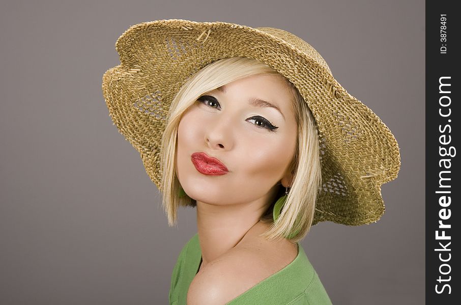A fresh young blonde model in a straw hat puckering for the camera. A fresh young blonde model in a straw hat puckering for the camera