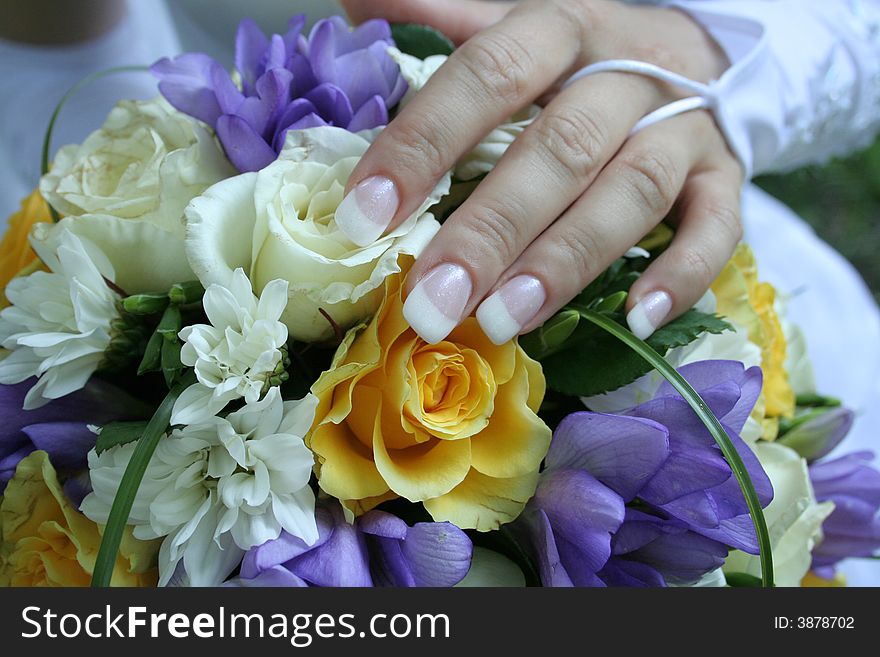 The gentle hand of the bride lays on a bouquet