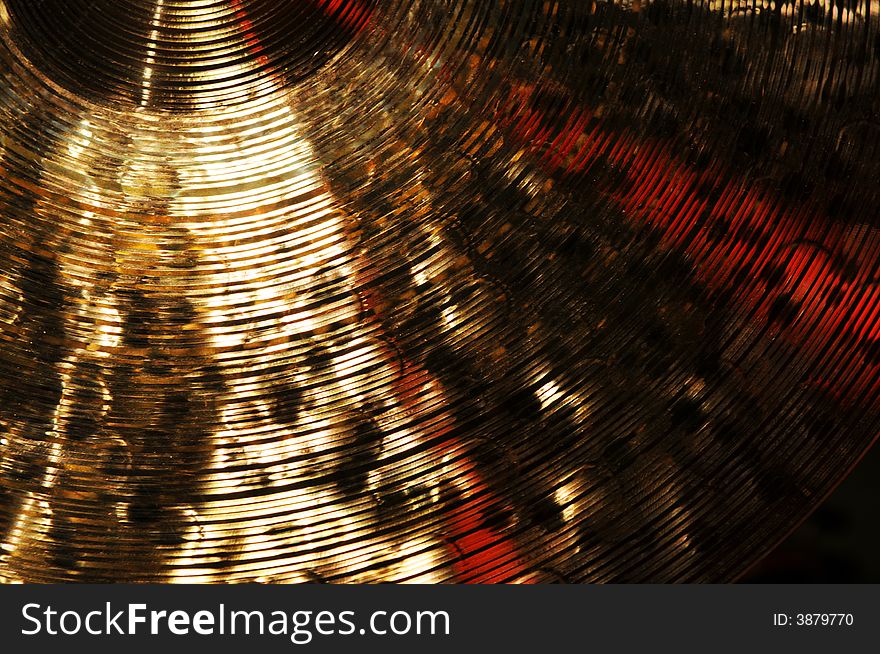Detail of brass cymbal with red light reflections. Detail of brass cymbal with red light reflections