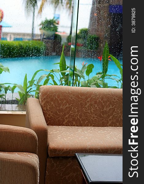 Sofa near by pool and window glass in rainy day