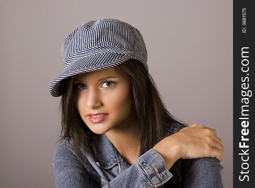 A beautiful brunette model with cap and hand on her shoulder. A beautiful brunette model with cap and hand on her shoulder