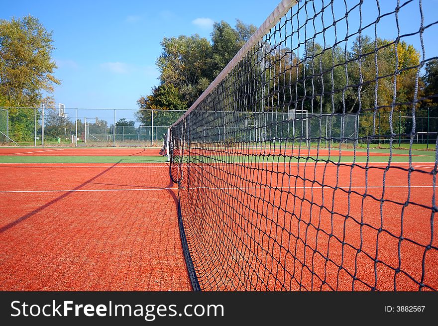 Tennis court under blue sky, with the net as leading line (wide angle)