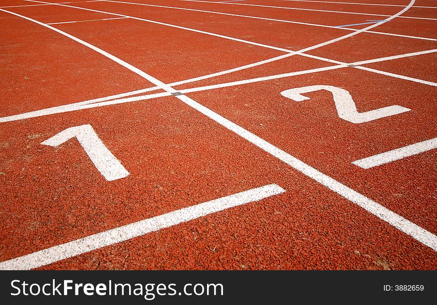 First two numbers of a racetrack, on red tarmac, for runners. First two numbers of a racetrack, on red tarmac, for runners