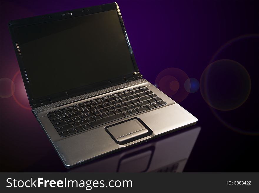 Laptop with refections and lens flare on a table. Laptop with refections and lens flare on a table