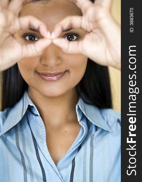 Businesswoman looking through circles made with her fingers. Businesswoman looking through circles made with her fingers