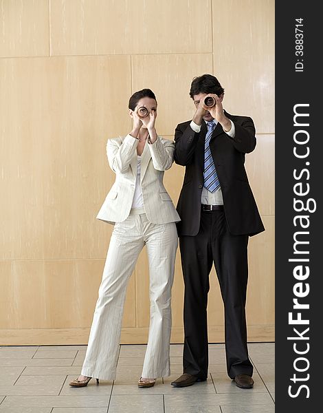 Businesswoman And Man Peering Through Tubes