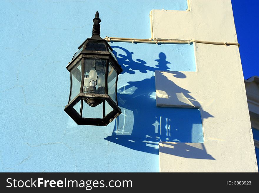 Black iron lantern hanging on a blue and white wall