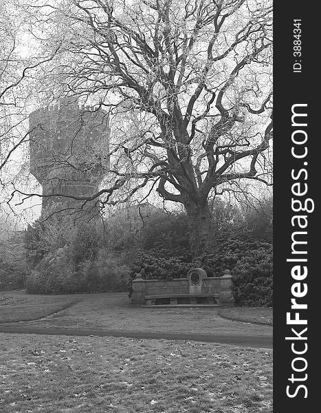 Stone bench in a park in winter, water tower in the background, vlack and white. Stone bench in a park in winter, water tower in the background, vlack and white