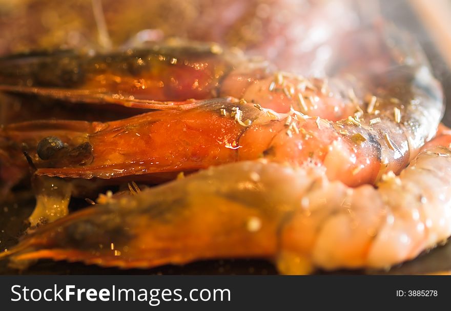 Fresh tiger prawns being cooked on a hot surface seasoned with salt and rosemary. Fresh tiger prawns being cooked on a hot surface seasoned with salt and rosemary