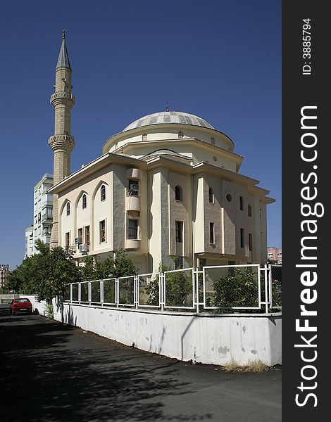 Ancient mosque with one minaret in the centre of a modern city