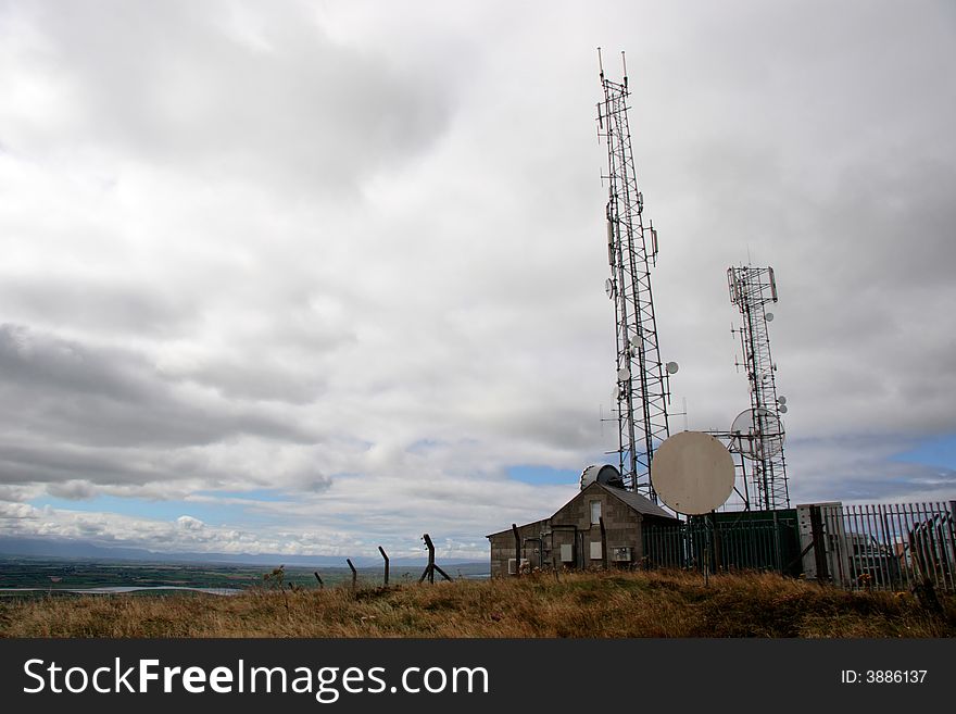 Communication masts and dishes on top of a hill. Communication masts and dishes on top of a hill