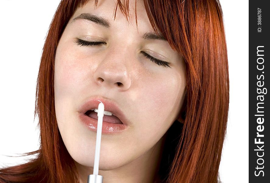 Cute redhead girl (close-up portrait) applying a shiny lipstick to her lips. Cute redhead girl (close-up portrait) applying a shiny lipstick to her lips.