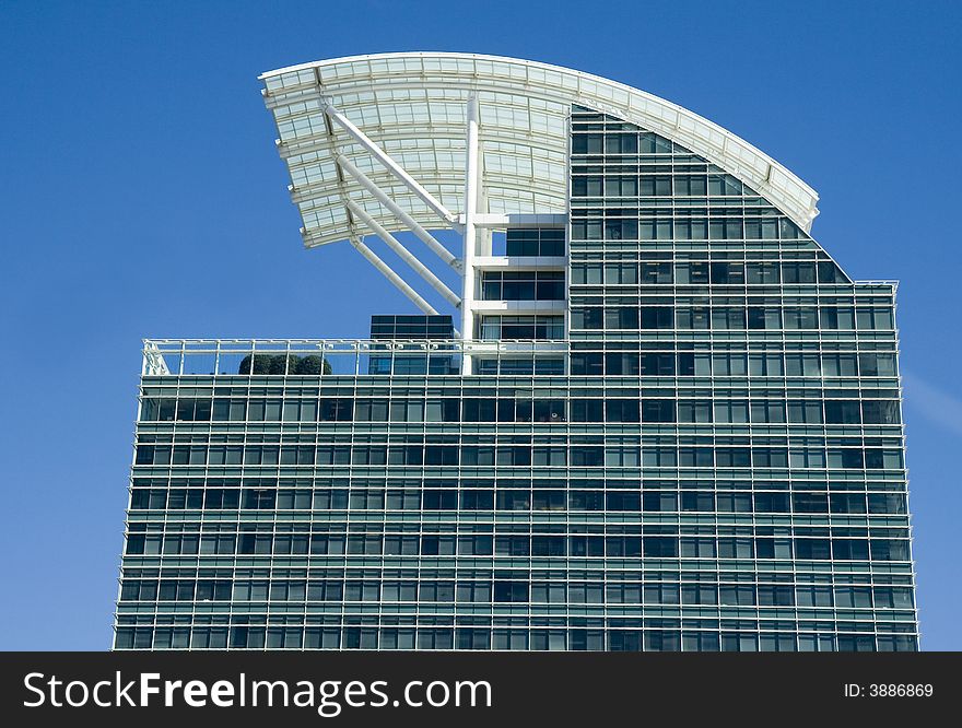 A modern blue glass office tower with a white curved roof. A modern blue glass office tower with a white curved roof