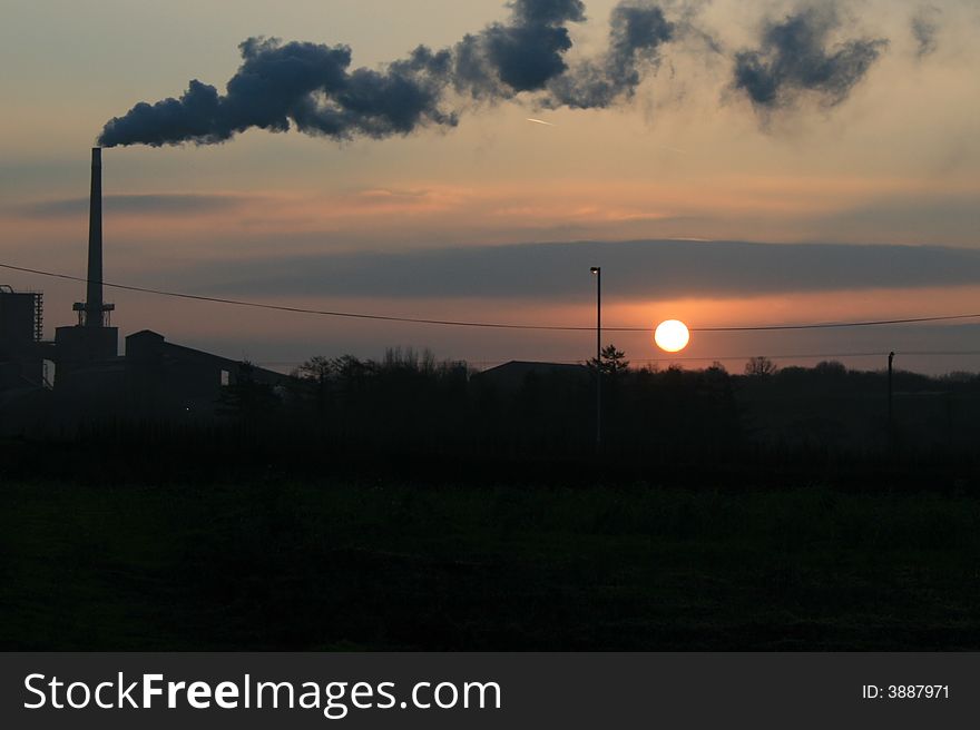 Factory chimney smoking at sunset