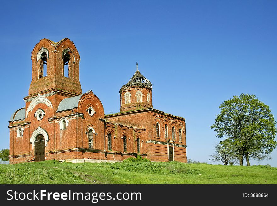 The destroyed orthodox church costs on a hill in the neighbourhood with an oak. The destroyed orthodox church costs on a hill in the neighbourhood with an oak