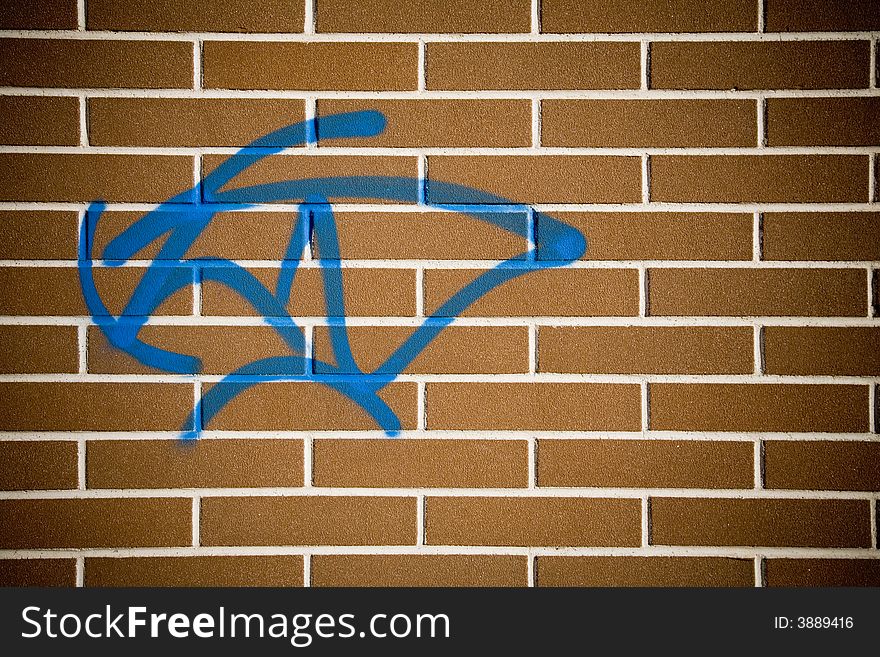 Photo of a plain red brick wall with a blue graffito. Photo of a plain red brick wall with a blue graffito