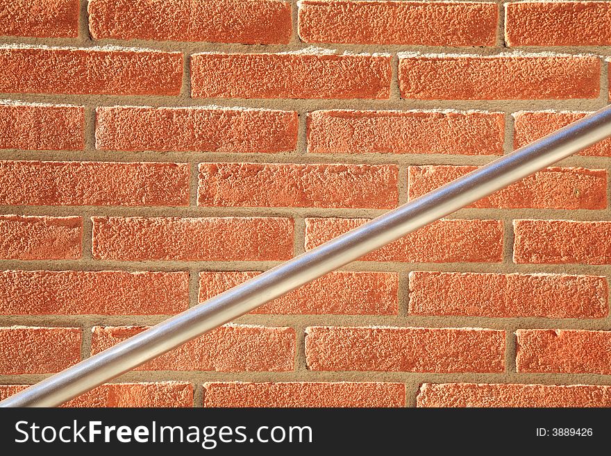 Photo of a plain red brick wall texture with diagonal metal handrail. Photo of a plain red brick wall texture with diagonal metal handrail