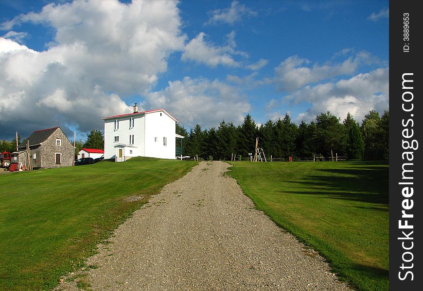 White typical country house beside a gravel road with a beautiful blue sky. White typical country house beside a gravel road with a beautiful blue sky.