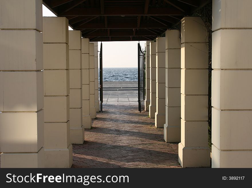 A small corridor under several columns out to the sea. A small corridor under several columns out to the sea
