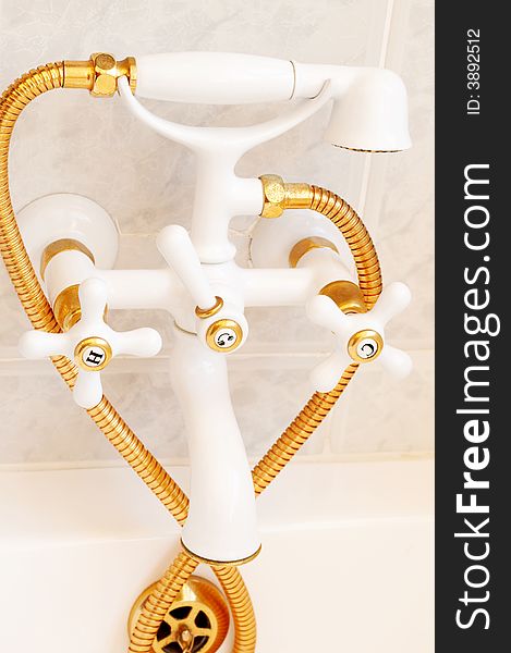 Beautiful gold and white decorative tap in a tiled bathroom. Beautiful gold and white decorative tap in a tiled bathroom