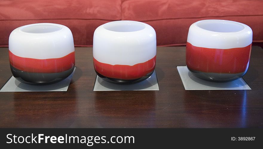 A row of red and white candles on a coffee table in front of a red sofa