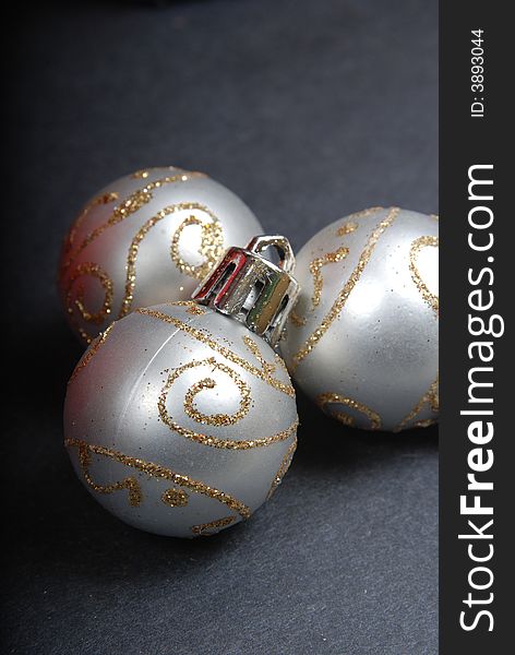 Three round Christmas ornaments with gold glitter decoration.