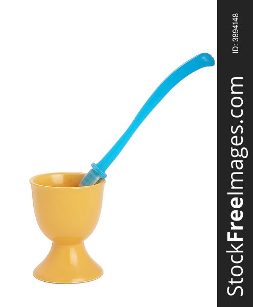 Yellow eggcup and  blue spoon isolated on white. Yellow eggcup and  blue spoon isolated on white
