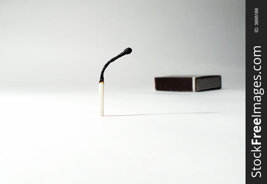 Burnt match standing on background with match-box. Burnt match standing on background with match-box