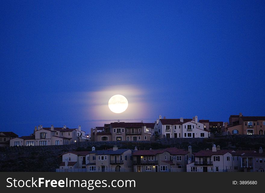 Full moon at 6:00 a.m. over roof tops. Full moon at 6:00 a.m. over roof tops