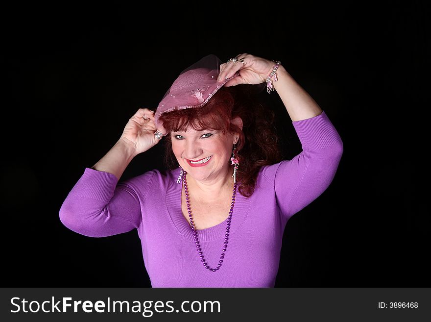 Beautiful red head woman wearing a pink hat isolated on black background. Beautiful red head woman wearing a pink hat isolated on black background